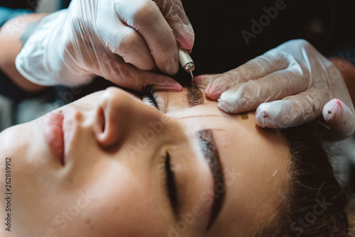 A young woman having her eyebrows micro bladed photo