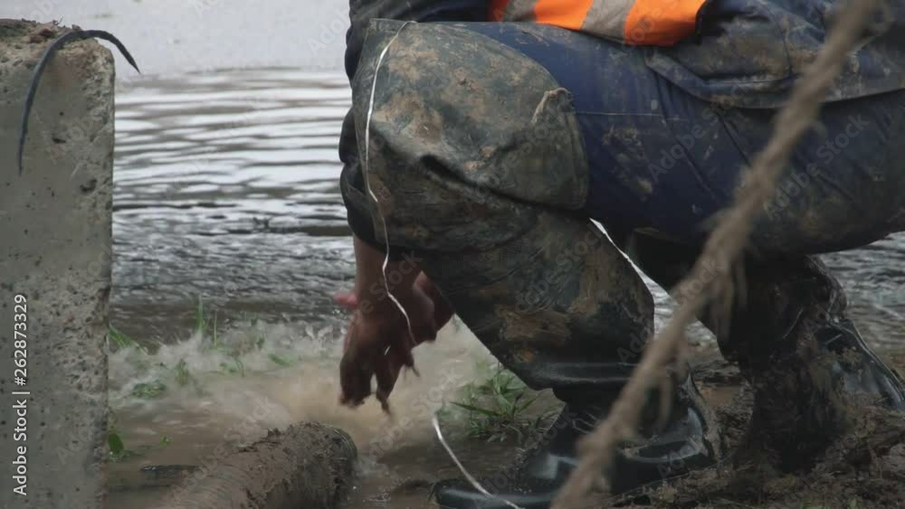 adult worker in a dirty uniform washing hands under water from a tube