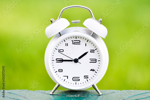 White alarm clock on green background. 