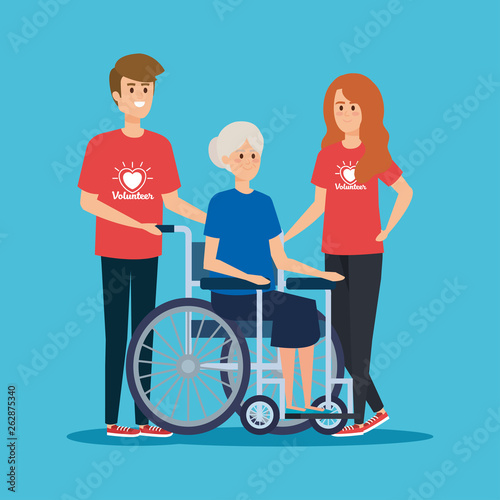 boy and girl volunteers with old woman in the wheelchair