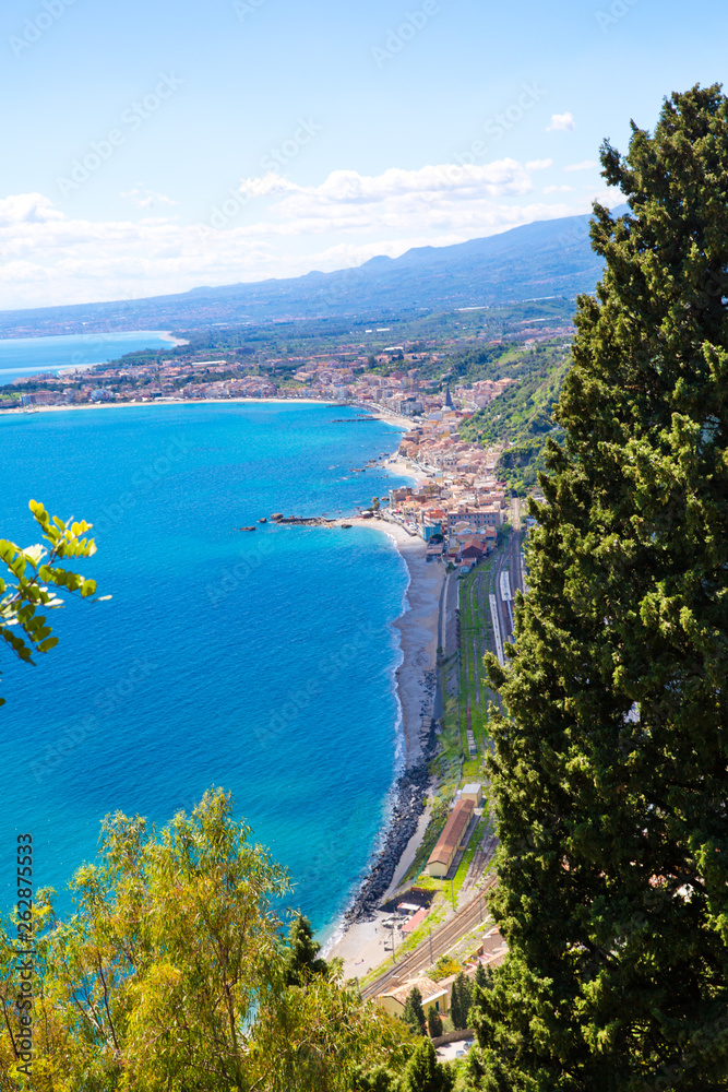 Crystal blue waters of Ionian sea near Taormina resorts and Etna volcano mount in Sicily, Italy. Shiny summer day, vacation destination. 
