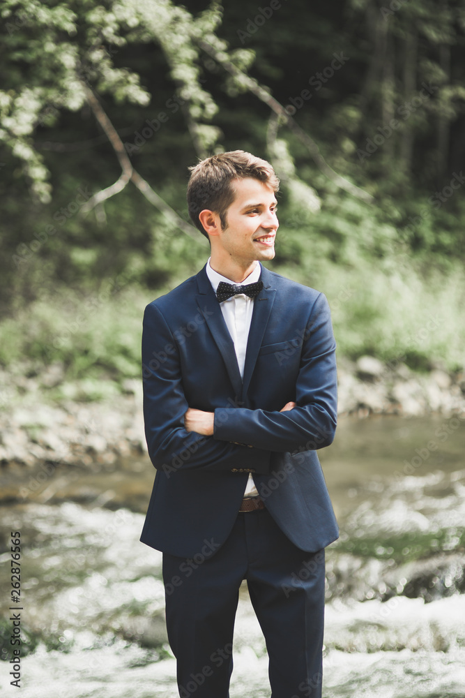 Young happy handsome man, groom posing outdoors