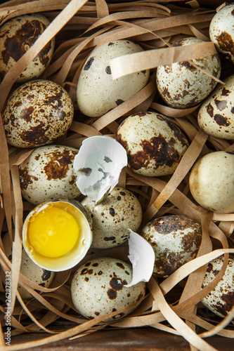 Quail eggs. Flat lay composition with small quail eggs on the natural wooden background. One broken egg with a bright yolk. photo