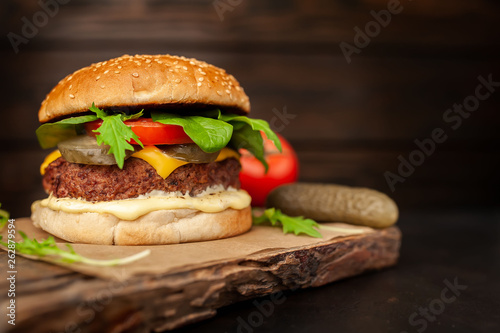 Homemade hamburger with lettuce, tomato, cheese and cucumber on a cutting board