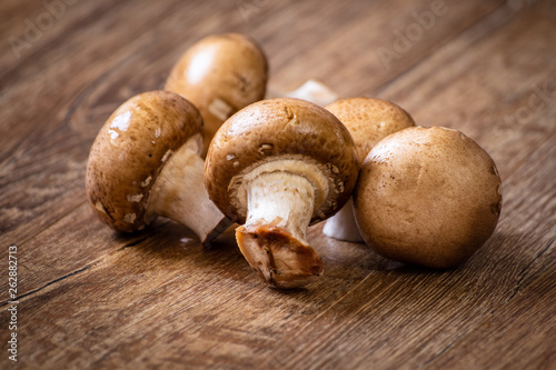 Fresh whole brown champignon mushrooms on vintage wooden table