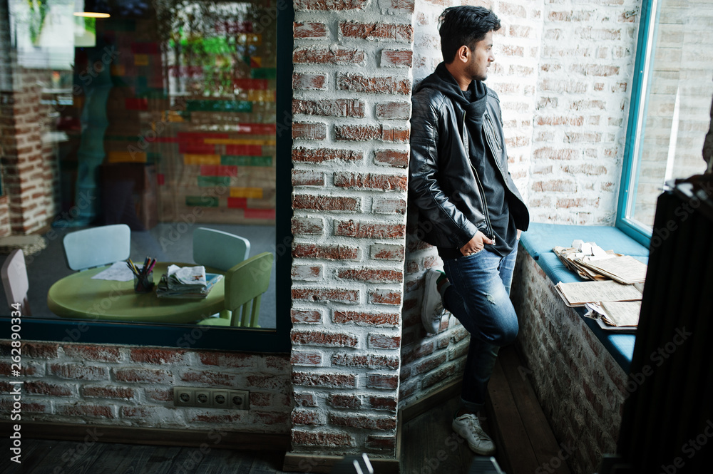 Smart young asian man wear on leather jacket posing against brick wall.