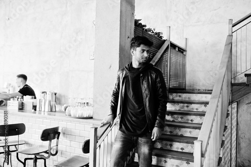 Casual and stylish young asian man wear on leather jacket standing on stairs at cafe.