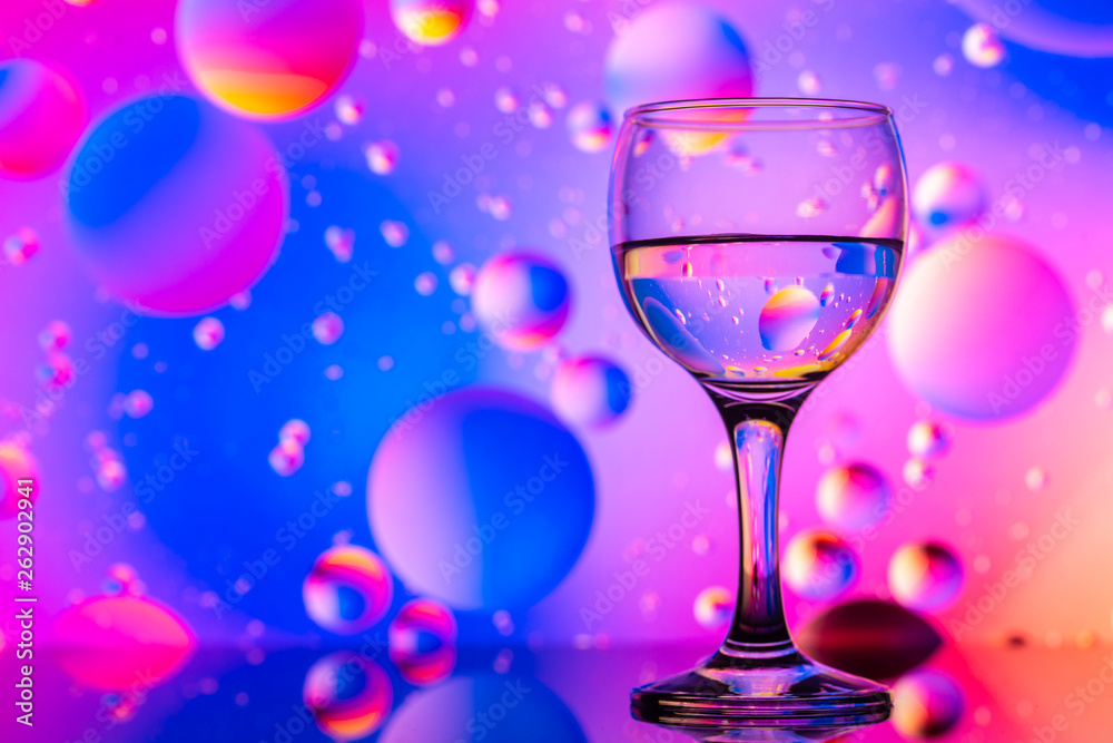transparent glasses with water and oily drops on colorful background transparent glasses with water and oily drops on colorful background