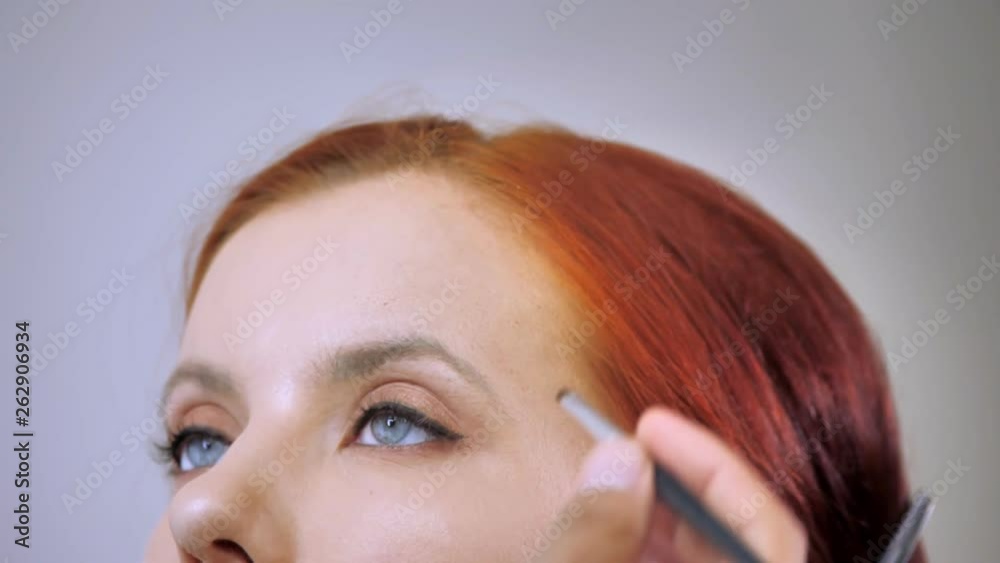 Make-up artist applying eyeliner on eye of a beautiful woman Make-up artist applying eyeliner on eye of a beautiful woman