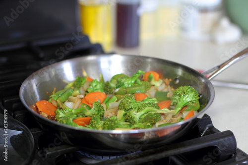 Stir fried vegetables cooking in a stainless steel pan.