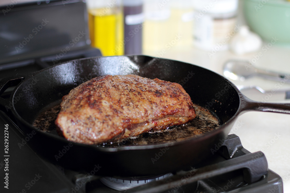 Tri-tip roast in a cast iron pan resting on the oven.