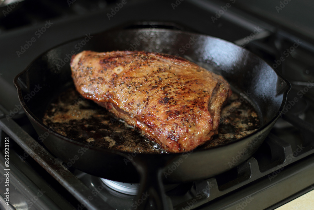 Tri-tip roast in a cast iron pan resting on the oven.
