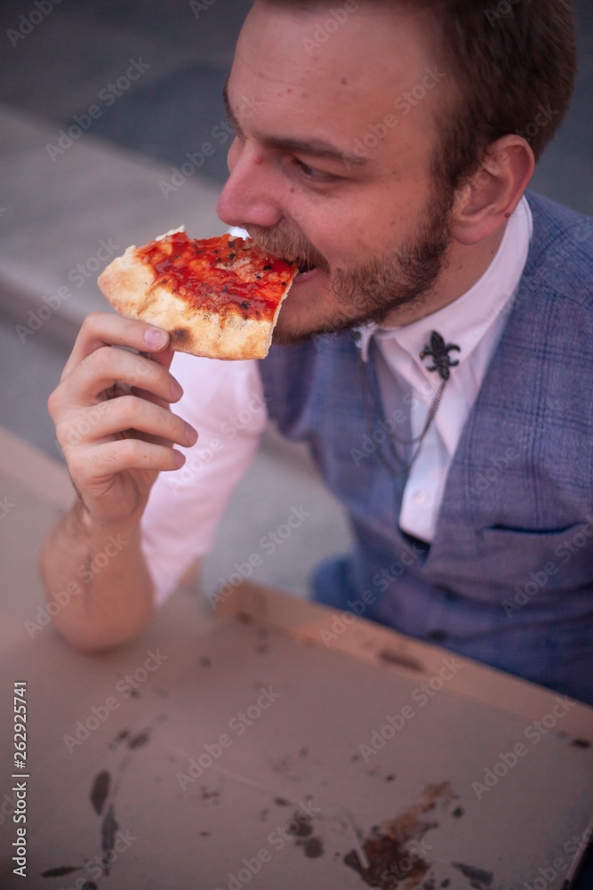 one young businessman eating a slice of pizza. one young businessman eating a slice of pizza.