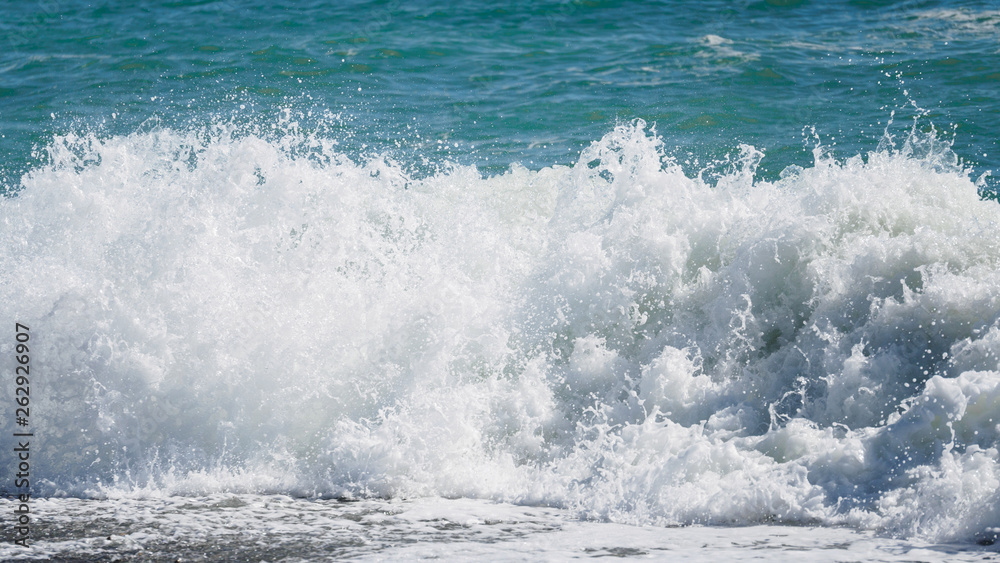Fototapeta premium Waves and splashes of water against the sea on a sunny summer day