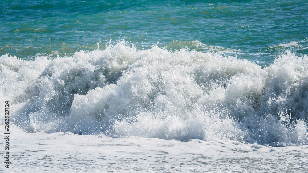 Fototapeta premium Waves and splashes of water against the sea on a sunny summer day