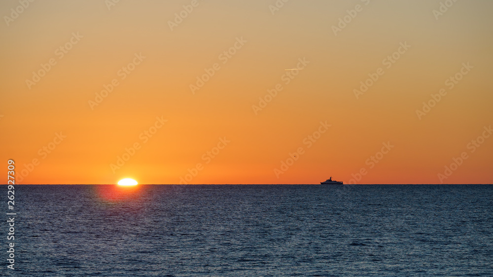 Orange sunset over the sea. The sun hides behind the horizon in the sea.