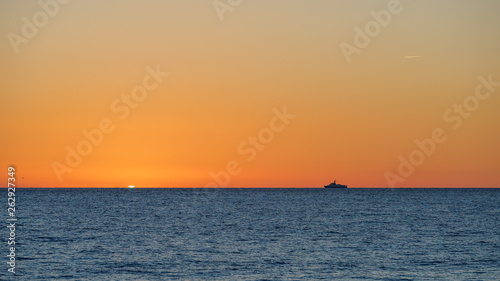 Orange sunset over the sea. The sun hides behind the horizon in the sea. © Dmitrii Potashkin