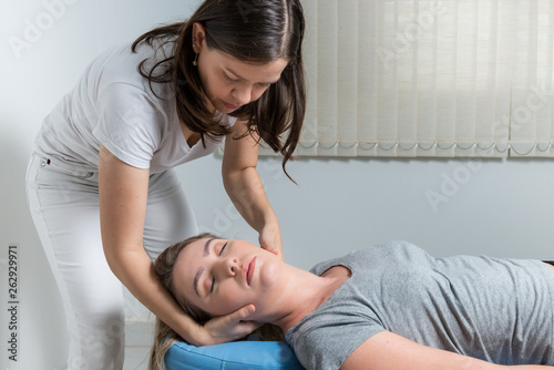 Blond Woman having chiropractic adjustment. Osteopathy, Alternative medicine, pain relief concept. Physiotherapy, sport injury rehabilitation. photo
