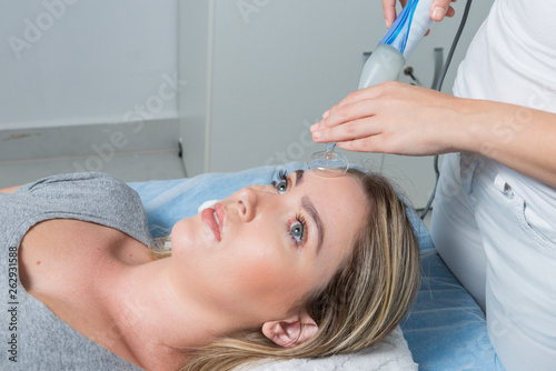 High frequency machine in spa salon. Young blond woman receiving electric darsonval facial massage after procedure at beauty room. Removal of acne from surface of face. Removing wrinkles.