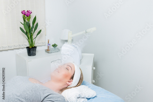 Beauty treatment of face with ozone facial steamer in beauty center. Beaultiful Blonde Girl.