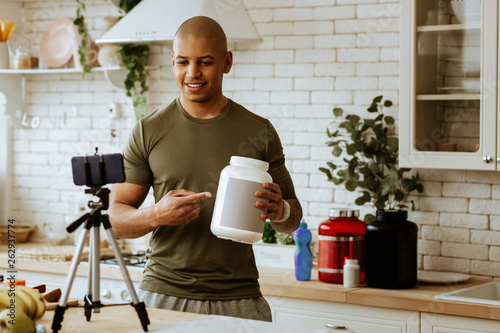 Tablou pe pânză Sportsman holding big pack of dietary protein filming video