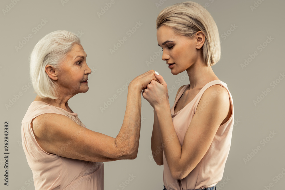 Pleasant young woman kissing her mothers hand Pleasant young woman kissing her mothers hand