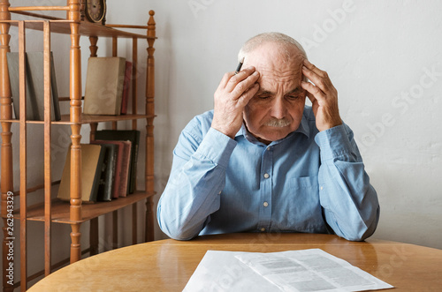 Depressed, concerned senior man doing paperwork