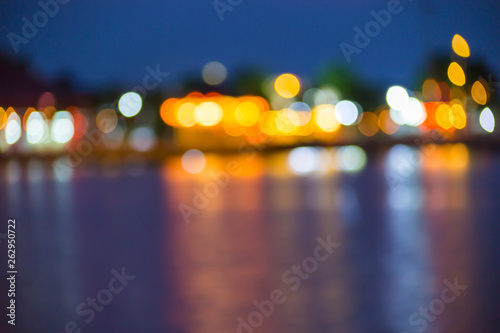 Beautiful blurred city lights with bokeh effect reflected on water © pandaclub23