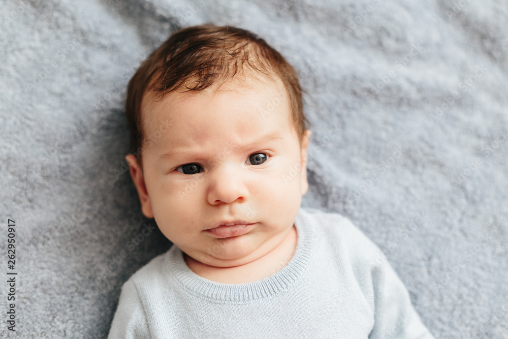 Cute baby seriously looking at the camera on a blue background Cute baby seriously looking at the camera on a blue background
