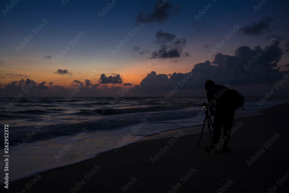 Silhuette men on the beach before sunrise.