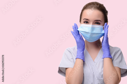 Beautiful female doctor or nurse wearing protective mask and latex or rubber gloves on light pink background isolated with copyspace. Health care concept