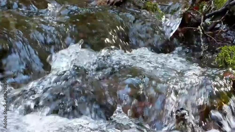 Water cascading over moss covered rocks in a mountain stream on a warm spring day Water cascading over moss covered rocks in a mountain stream on a warm spring day
