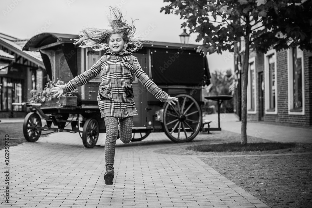 Naklejka premium Little fashionable girl in warm clothes walk outdoor, Autumn - Winter season, holidays and children concept. Sweet girl at European street 