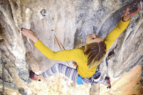 Fototapeta Naklejka Na Ścianę i Meble -  The girl climbs the rock. Fitness in nature and rock climbing. The climber climbs up.