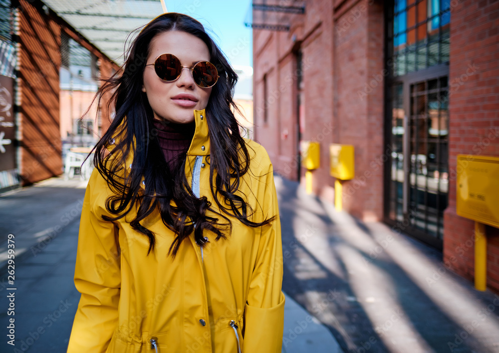 Fototapeta premium young woman in yellow raincoat at city street