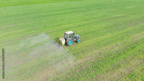 Tractor with sprayer treats wheat field with herbicides for removing weeds. Agronomic activities on farm photo