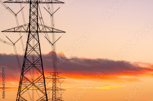 High voltage electric pole and transmission lines in the evening. Electricity pylons at sunset. Power and energy. Energy conservation. High voltage grid tower with wire cable at distribution station.