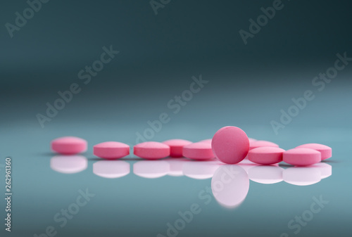 Round pink tablets pill on gradient background. Vitamins and minerals plus folic acid vitamin E and zinc in drug bottle on gradient background. Pink tablets pills for during and after pregnancy woman.