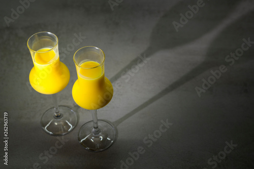 Two glasses of egg liqueur on dark grey or black texture background photo