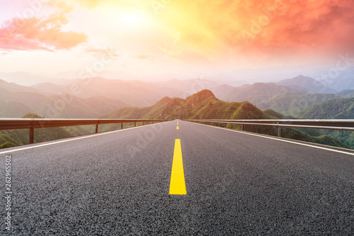 Empty asphalt road and mountains with beautiful clouds at sunset photo