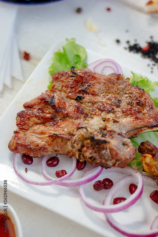 Barbecue ribs on white plate, meat dish served with onion and herbs. Barbecue ribs on white plate, meat dish served with onion and herbs.