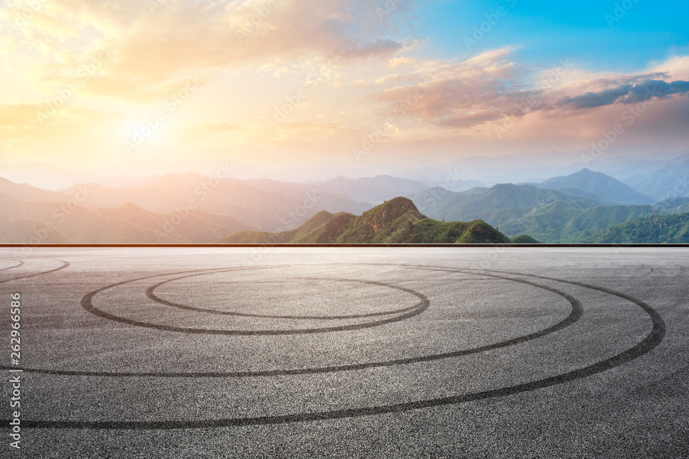 Asphalt race track ground and mountain with sunset clouds Asphalt race track ground and mountain with sunset clouds