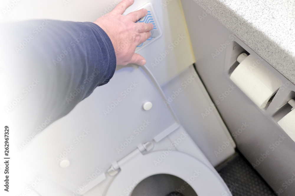 person hand press flush button to clean toilet in airplane bathroom interior top down view of passenger aircraft air travel equipment in modern water closet WC with open seat detail inside plane cabin person hand press flush button to clean toilet in airplane bathroom interior top down view of passenger aircraft air travel equipment in modern water closet WC with open seat detail inside plane cabin