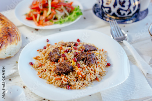 Traditional asian and oriental pilaf or plov with meat on the white plate.