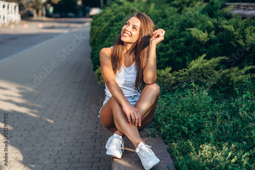 Pretty young smiling brunette girl relaxing outdoor on the street.