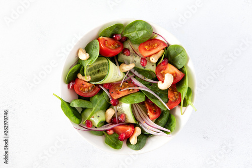 Healhty vegan lunch bowl with salad with spinach, tomato, cucumber, onion, cashew nuts, pomegranate and sesame with olive oil photo