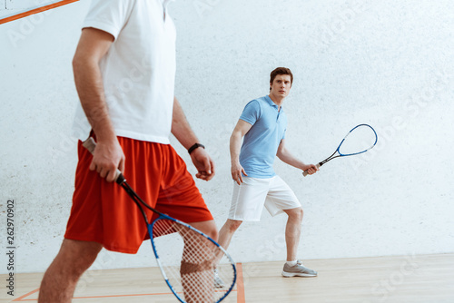 Cropped view of squash players with rackets in four-walled court © LIGHTFIELD STUDIOS