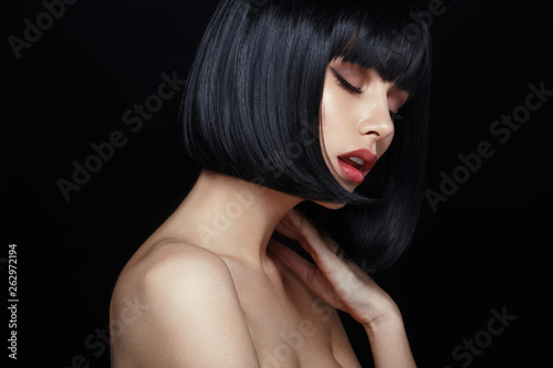 Tela Profile portrait of a sensual young woman in black wig, bob haircuts, she touches his neck, have closed eyes, make up, big lips, naked shoulders, isolated on a black background