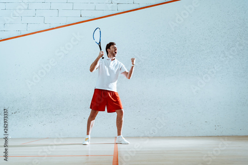 Full length view of happy squash player with racket showing yes gesture