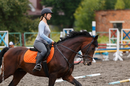 Young girl riding bay horse on equestrian sport training